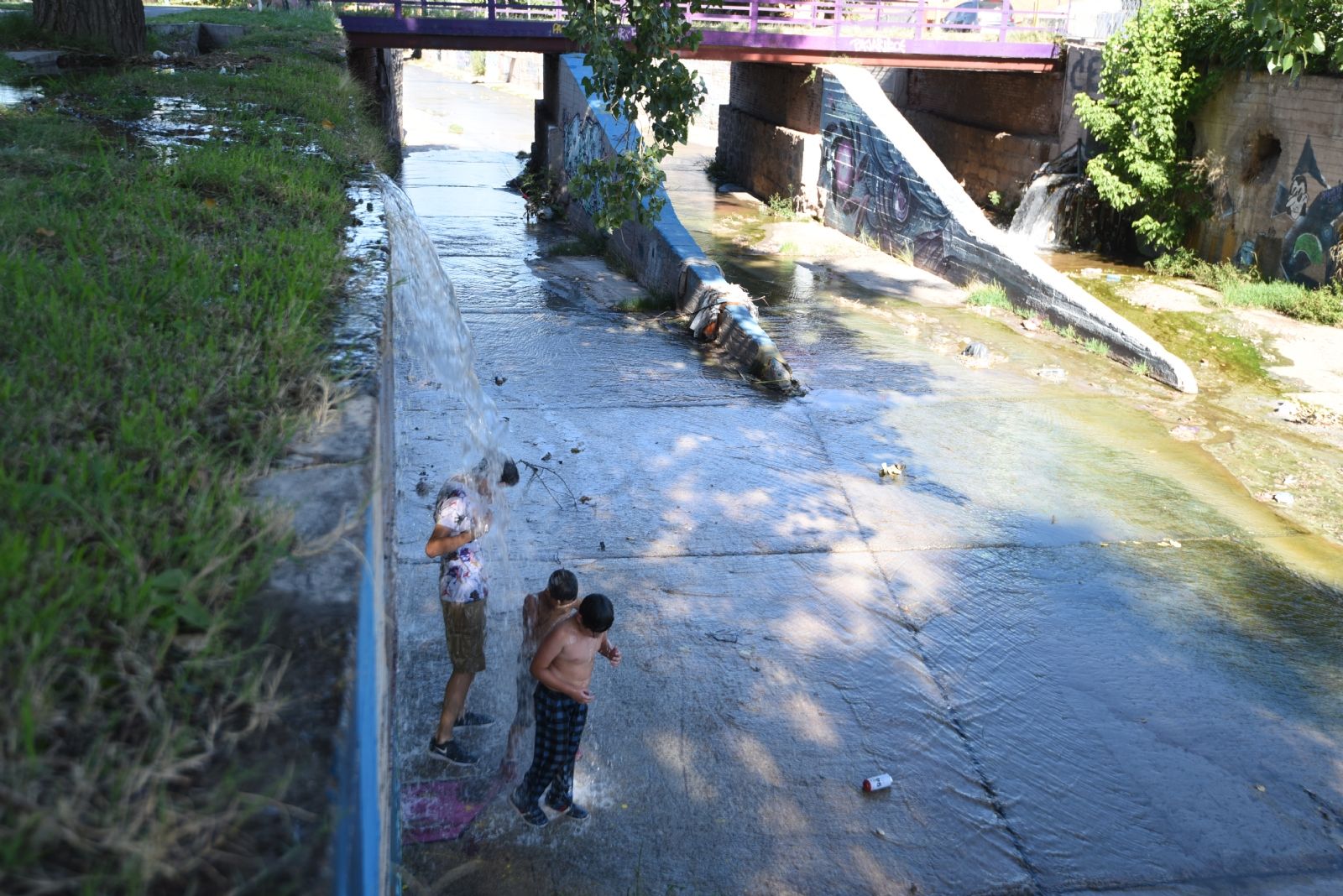 Tres niños se bañaban esta tarde bajo el agua que caía sobre el zanjón Maure