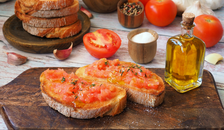 La receta de pan tumaca nació en Cataluña a principios del siglo XX, cuando los campesinos frotaban tomates maduros en el pan duro para ablandarlo y aprovechar los ingredientes disponibles.