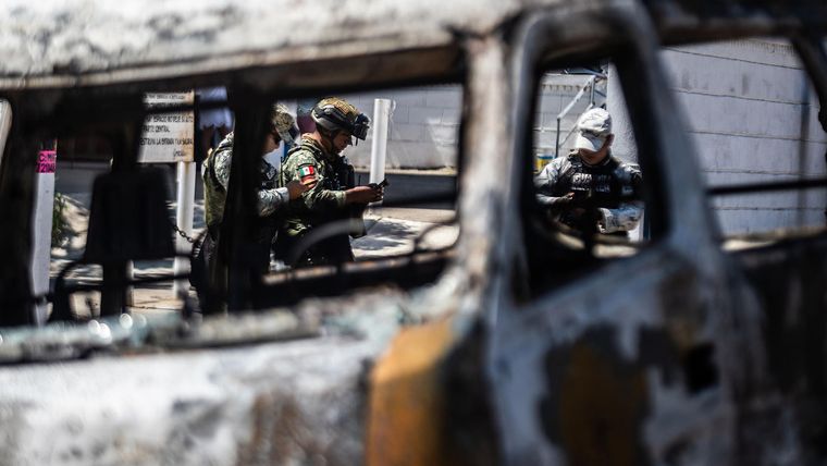 &nbsp;Integrantes de la Guardia Nacional y el ejército mexicano vigilan la zona donde fue incendiado un autobús por presuntos integrantes del crimen organizado este domingo, en el balneario de Acapulco (México).