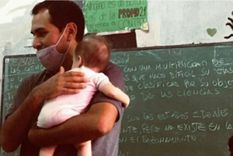 profesor sostiene a la bebe de su alumna para que pueda estar en clase