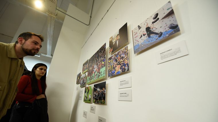Los asistentes a la muestra de aRGra viendo la foto de MDZ en el mural de la sección deportes.&nbsp;