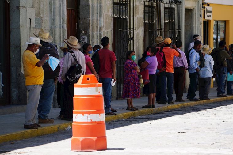 Varias personas hacen fila este lunes para hacer trámites en un banco de Oaxaca (México). EFE/ Daniel Ricardez