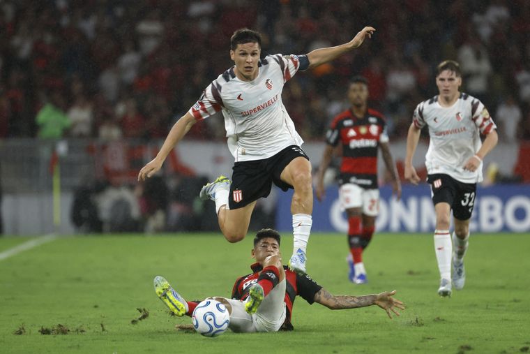 Guido Carrillo, delantero de Estudiantes, se escapa del mediocampista colombiano de Flamengo, Jorge Carrascal, quien va con todo al suelo para intentar detenerlo.&nbsp;