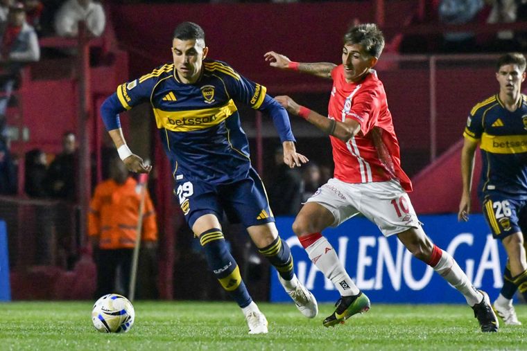 Rodrigo Battaglia (29), volante central de Boca, se lleva el balón ante la presión de Alan Lescano (10), de Argentinos Juniors.