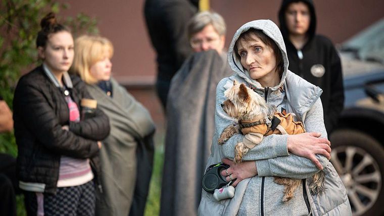 Una mujer sostiene a su perro en un vecindario bombardeado en Kyiv.
