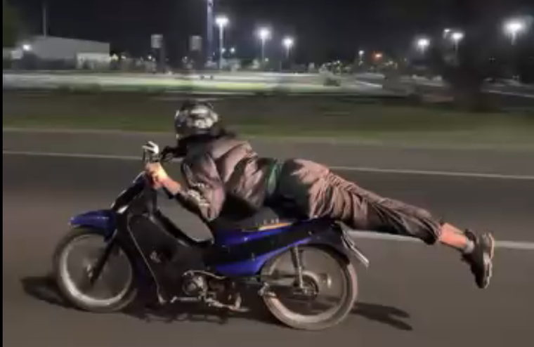 El motociclista acostado sobre su moto.