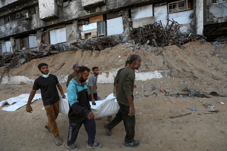 Gazatíes recuperan los cadáveres de sus familiares fallecidos durante la guerra.