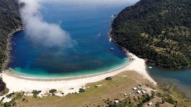 La costa del pueblo muestra arena clara y aguas que cambian de color según la luz.