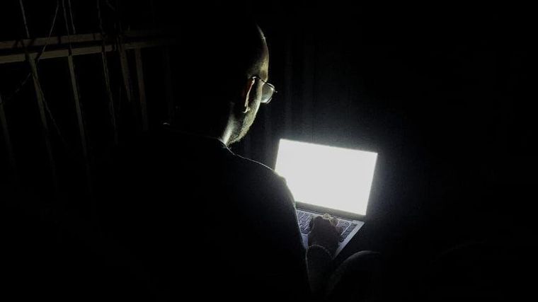 Gustavo suele pasar los largos apagones leyendo o escribiendo en su computador en el balcón de su casa.