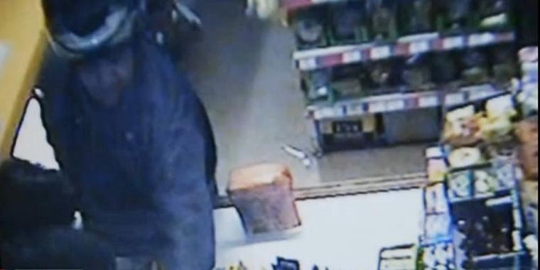 Momento en que el asaltante apunta a la cajera.