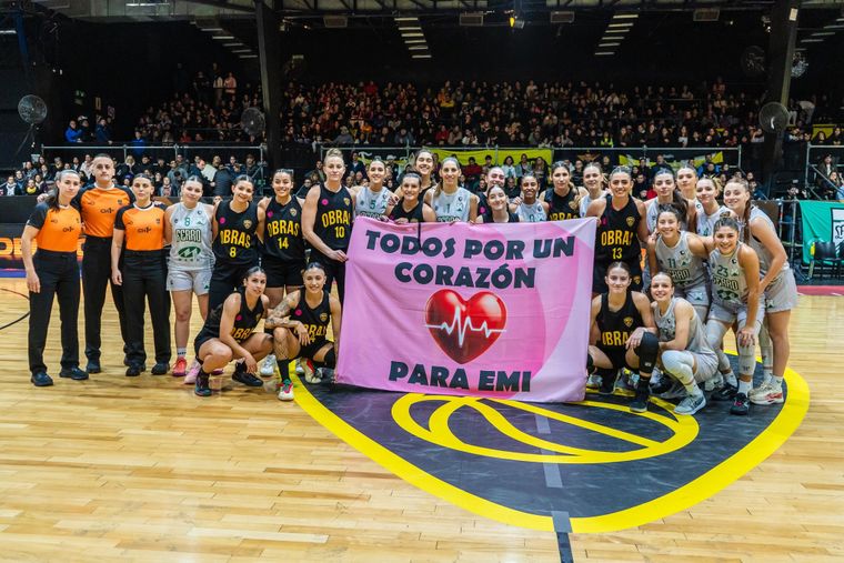 Las jugadoras de Obras Sanitarias y Ferro Carril Oeste en la previa del segundo partido de la Liga Nacional Femenina desplegaron un cartel para apoyar a Emi Troncoso. 