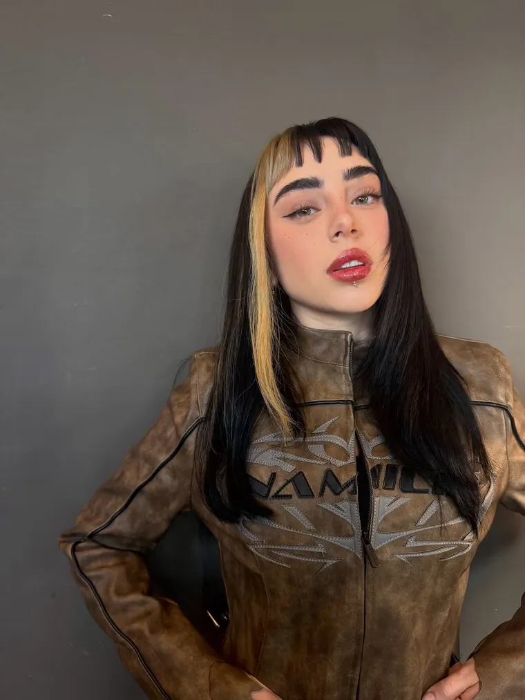 El flequillo desmechado, la mecha rubia y el make up con labios rojos brillantes. El flequillo desmechado, la mecha rubia y el make up con labios rojos brillantes.