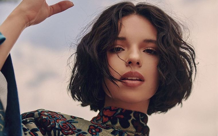 Ángela Aguilar eligió una media polera de mangas largas en un género aterciopelado para combinar con su falda negra con dibujos coloridos. Foto: Revista Fama - cdn.revistafama.com