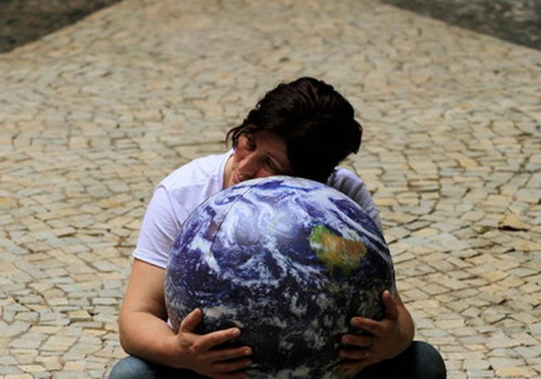 Una manifestante abraza una réplica del mundo frente a la cumbre. Foto: reuters