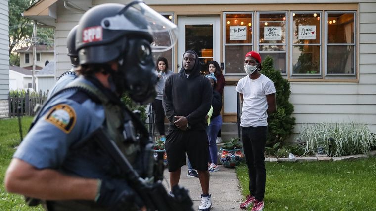 Manifestantes observan pasar a unos agentes de Policía por una calle residencial en St. Paul (Minnesota, EE.UU.), el 28 de mayo de 2020.