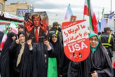 Mujeres iraníes marchan con un cartel que representa al presidente estadounidense Donald Trump con las manos ensangrentadas en Teherán, febrero de 2026.