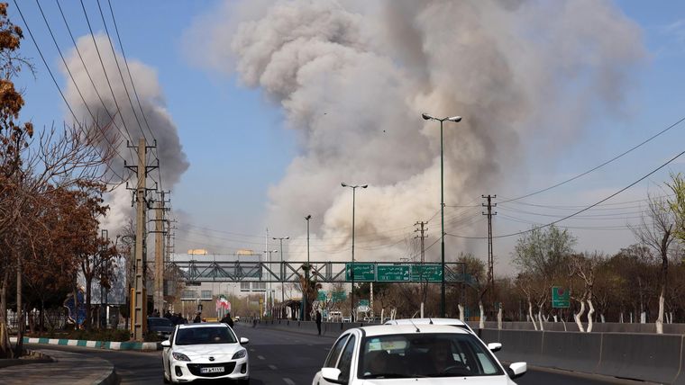 La gente corre en busca de refugio mientras el humareda se eleva tras un ataque aéreo en el centro de Teherán, Irán, este jueves.