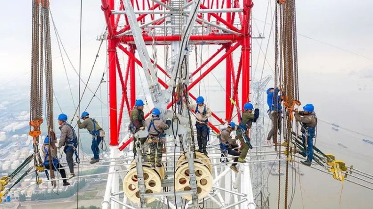 Los trabajadores construyen una línea eléctrica de ultra alto voltaje (UHV) junto al río Yangtze de China. Foto: Getty Images