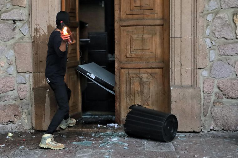 Un manifestante causando destrozos en el Palacio de Gobierno de Morelia, en México.
