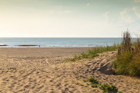 Las pasarelas del pueblo atraviesan médanos antes de abrirse al océano.