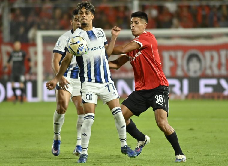 Ronaldo Martínez (77), delantero de Talleres, intenta cubrir el balón frente a la marca del defensor de Independiente, Sebastián Valdez (36). 