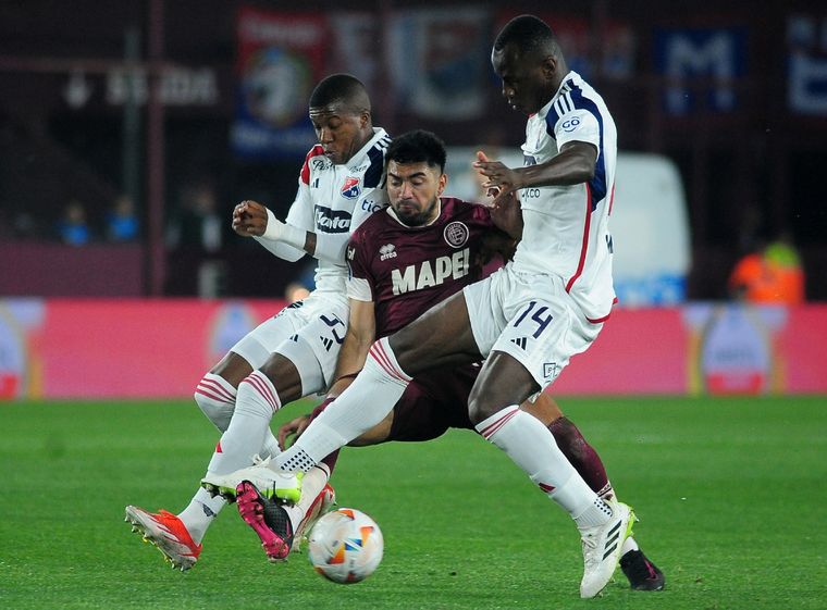 Marcelino Moreno intenta pasar con la marca de dos futbolistas del DIM. Foto: ForoBaires
