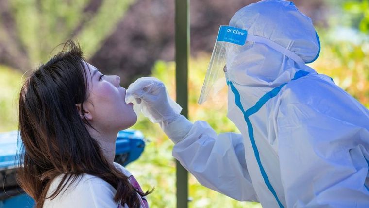 Un sanitario toma una muestra a una estudiante en la Universidad de Wuhan para hacerle un test de coronavirus.