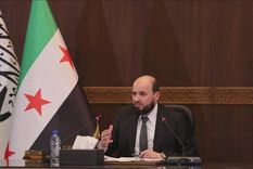 Mohamed al Bashir, el primer ministro del nuevo gobierno de transición de Siria, junto a la controvertida bandera. Foto: BBC