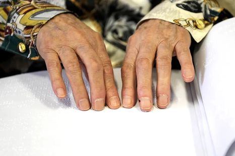 Una mujer leyendo la biblia en braille.