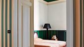 En la imagen el método sándwich representado en una habitación con un verde fuerte y estampado en las partes superior (techo) e inferior (empapelado) con un contraste brillante y claro en la pared, cama y puerta. Foto: Farrow & Ball
