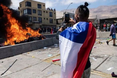 Un ciudadano toma una imagen de la quema de ropa y pertenencias de los migrantes que han llegado a Iquique en los últimos meses. Foto: GETTY IMAGES