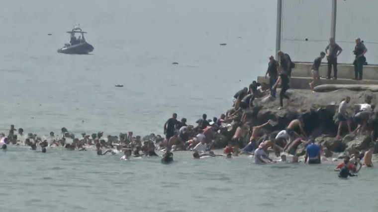 Migrantes cruzan a nado la frontera española de Ceuta desde el lado marroquí y trepan por las rocas para llegar a la valla fronteriza, en Ceuta, España, el 30 de julio de 2026.