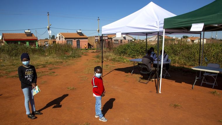 Niños hacen cola en un campo de fútbol para ser examinados por el covid-19 en Johannesburgo, Sudáfrica.
