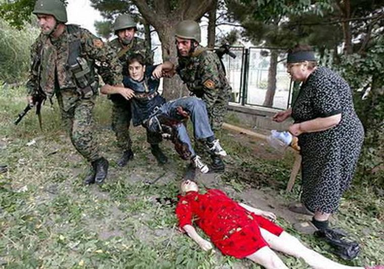 Tres soldados recogen a un niño herido ante el cuerpo sin vida de una mujer, tras el ataque aéreo ruso. Foto: EFE