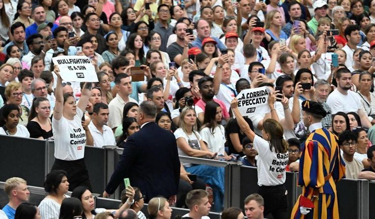 Las activistas mostrando sus carteles en la audiencia del papa. Foto: Efe.