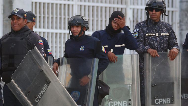 Integrantes del Cuerpo de Policía Nacional Bolivariana (CPNB) custodian una calle en Caracas . Integrantes del Cuerpo de Policía Nacional Bolivariana (CPNB) custodian una calle en Caracas .