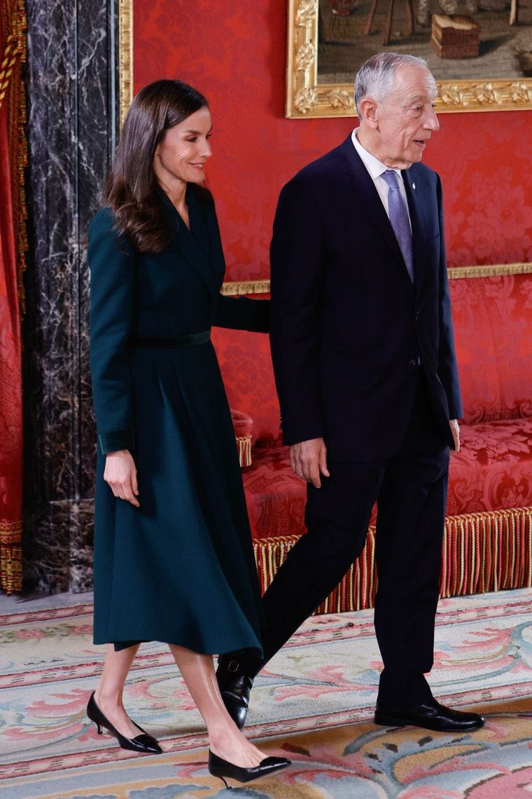 Abrigo verde pino cruzado y elegancia clásica en una recepción oficial.