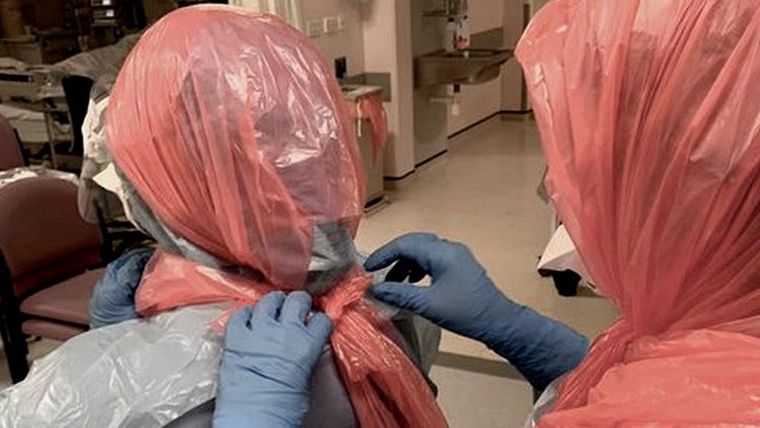 La doctora Roberts ayuda a sus colegas a ponerse bolsas de basura en la cabeza.