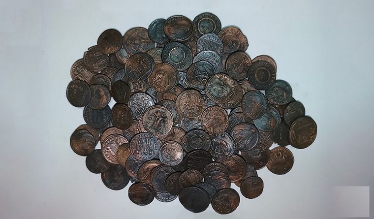 Un puñado de las miles de monedas de bronce encontradas. Foto: Efe.