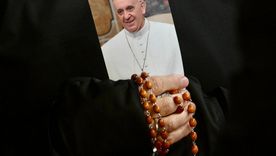 Una monja sostiene una imagen del Papa Francisco y un rosario mientras los fieles asisten a una oración por la salud del pontífice. Foto: EFE