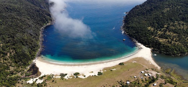 La costa del pueblo muestra arena clara y aguas que cambian de color según la luz.