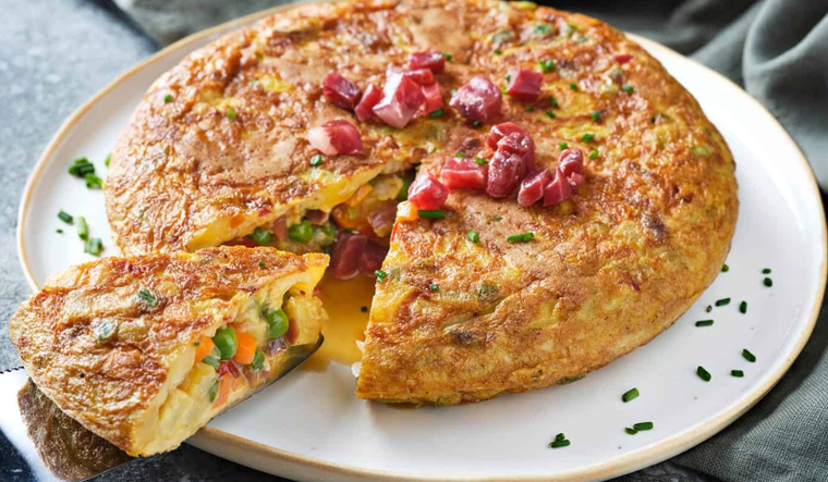 La receta de tortilla paisana nació como una variante campesina de la tortilla española, aprovechando verduras y embutidos disponibles en cada temporada, lo que hace que ninguna receta sea exactamente igual.
