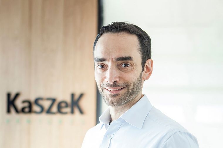 Kazah, delante de su firma