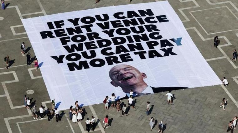 "Si puedes alquilar Venecia para tu boda, puedes pagar más impuestos", dice una pancarta contra Jeff Bezos.