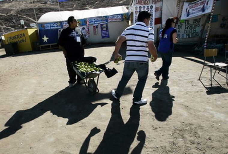 Voluntarios residentes reparten fruta en el campamento Esperanza. Foto: EFE