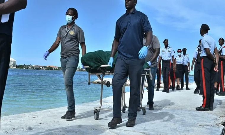 El personal de los servicios funerarios retira el cuerpo de una mujer que murió tras ser atacada por un tiburón toro cerca de Green Cay.  Foto: TORRELL GLINTON