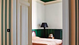 En la imagen el método sándwich representado en una habitación con un verde fuerte y estampado en las partes superior (techo) e inferior (empapelado) con un contraste brillante y claro en la pared, cama y puerta. Foto: Farrow & Ball
