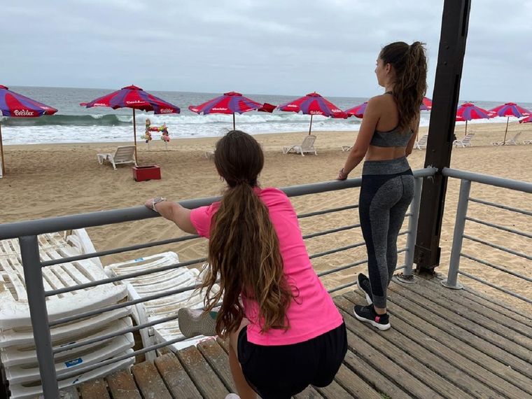 Maca y Ale elongan con una playa vacía frente a ellas.