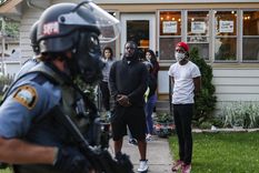 Manifestantes observan pasar a unos agentes de Policía por una calle residencial en St. Paul (Minnesota, EE.UU.), el 28 de mayo de 2020.