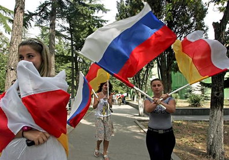 Una mujer ondea las banderas nacionales de Rusia y Osetia del Sur. Foto: EFE